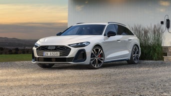 Ein weißer A5 Avant e-hybrid steht vor einer weißen Hauswand. Im Hintergrund sind Berge und Wolken zu sehen.