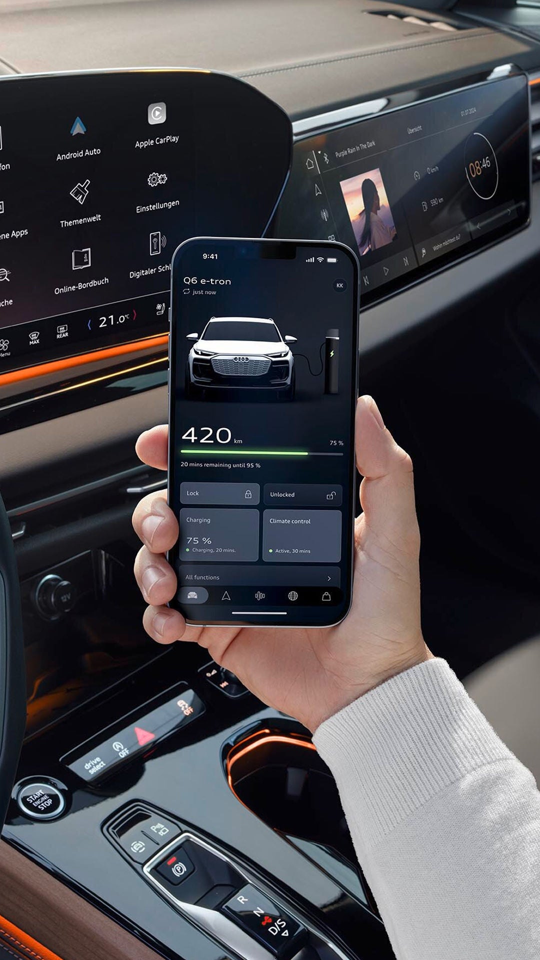 A hand holding a mobile phone with the myAudi app displayed on its screen