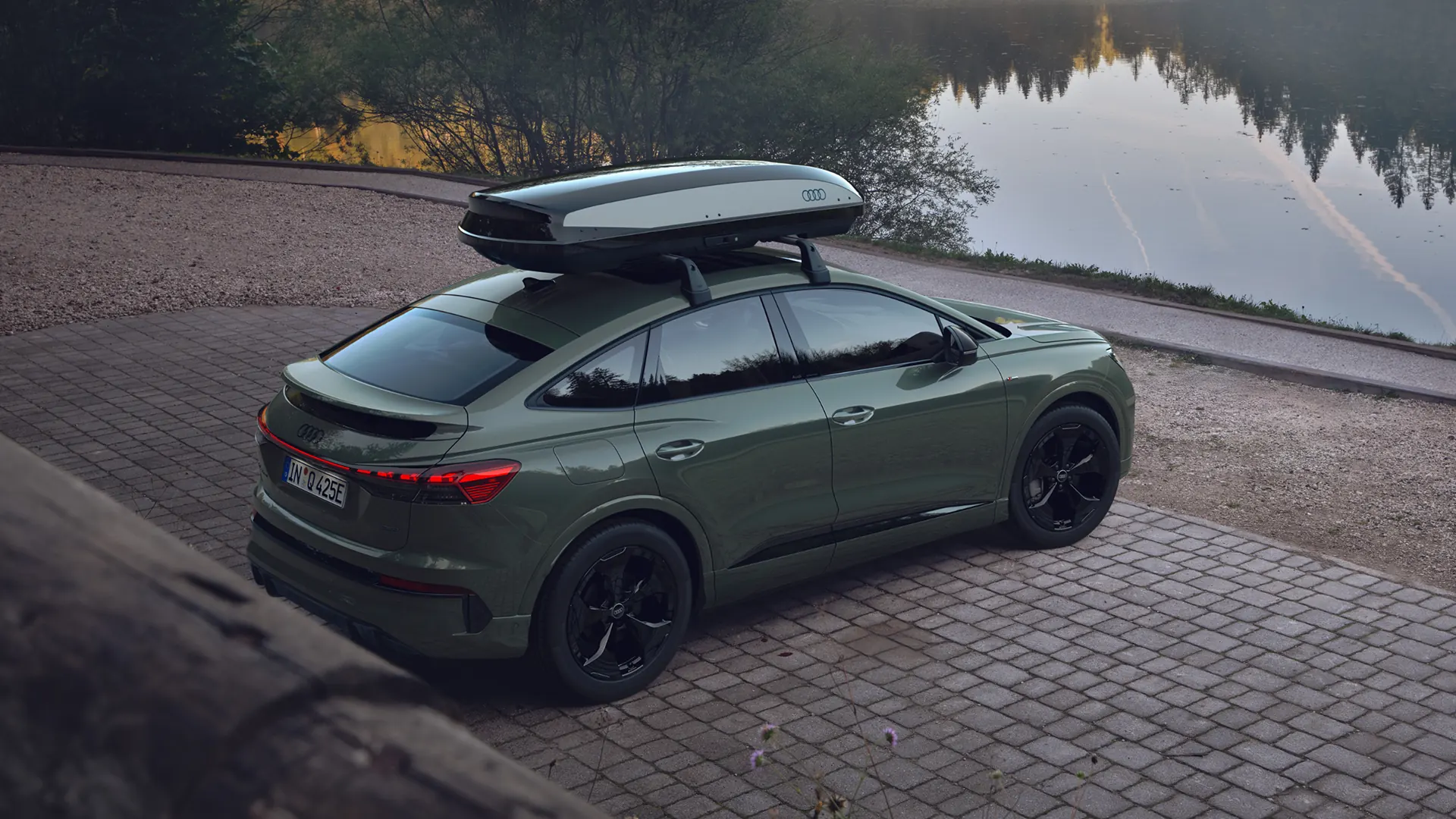 Grey Audi {Model Name} facing front, parked on tarmac in front of building with patterned facade.