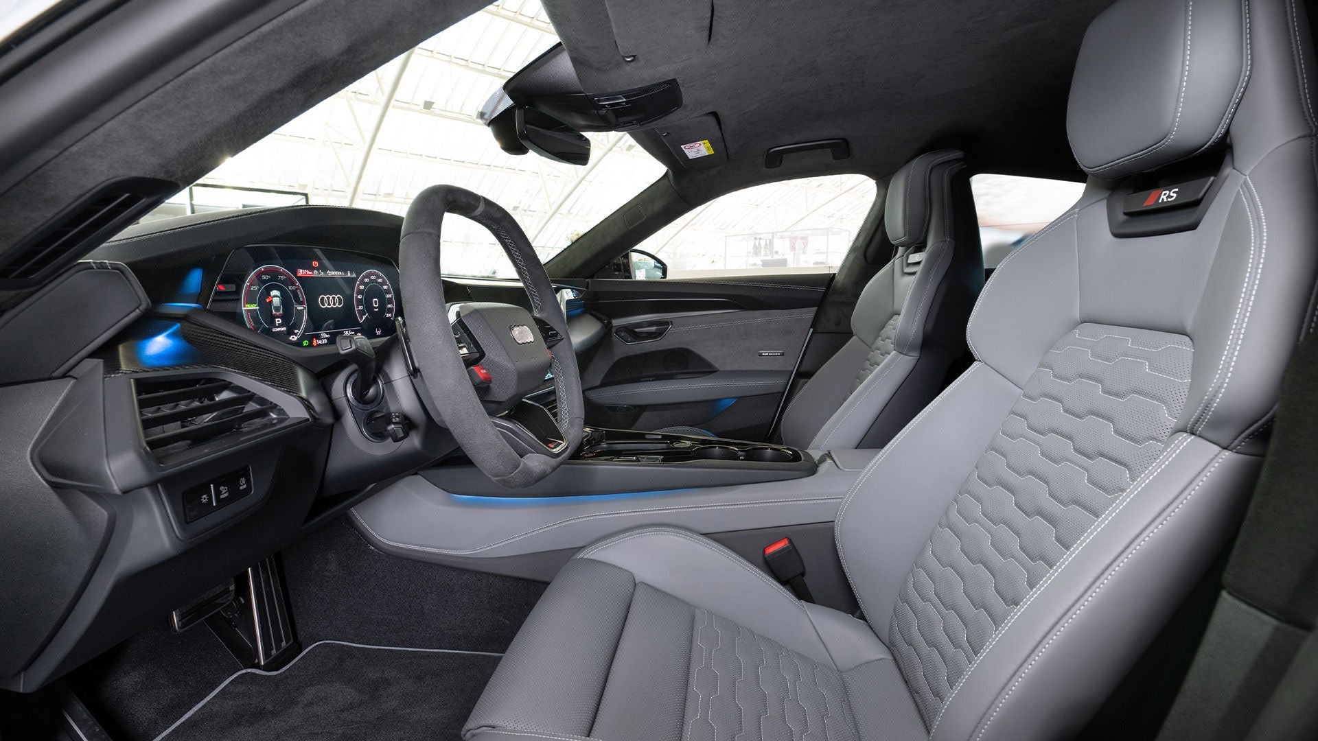 Car interior with grey leather seats, sport steering wheel, and displays.