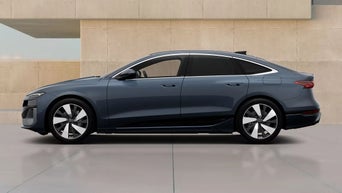 An Audi New A6 Sportback e-tron parked against a modern, minimalist backdrop of beige walls, showcasing its contemporary design and smooth lines.