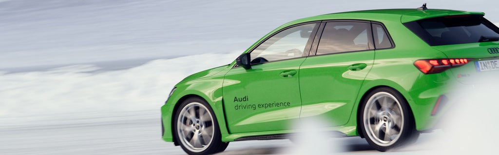 Light green Audi RS 3 Sportback from the side while driving on a snow-covered track.