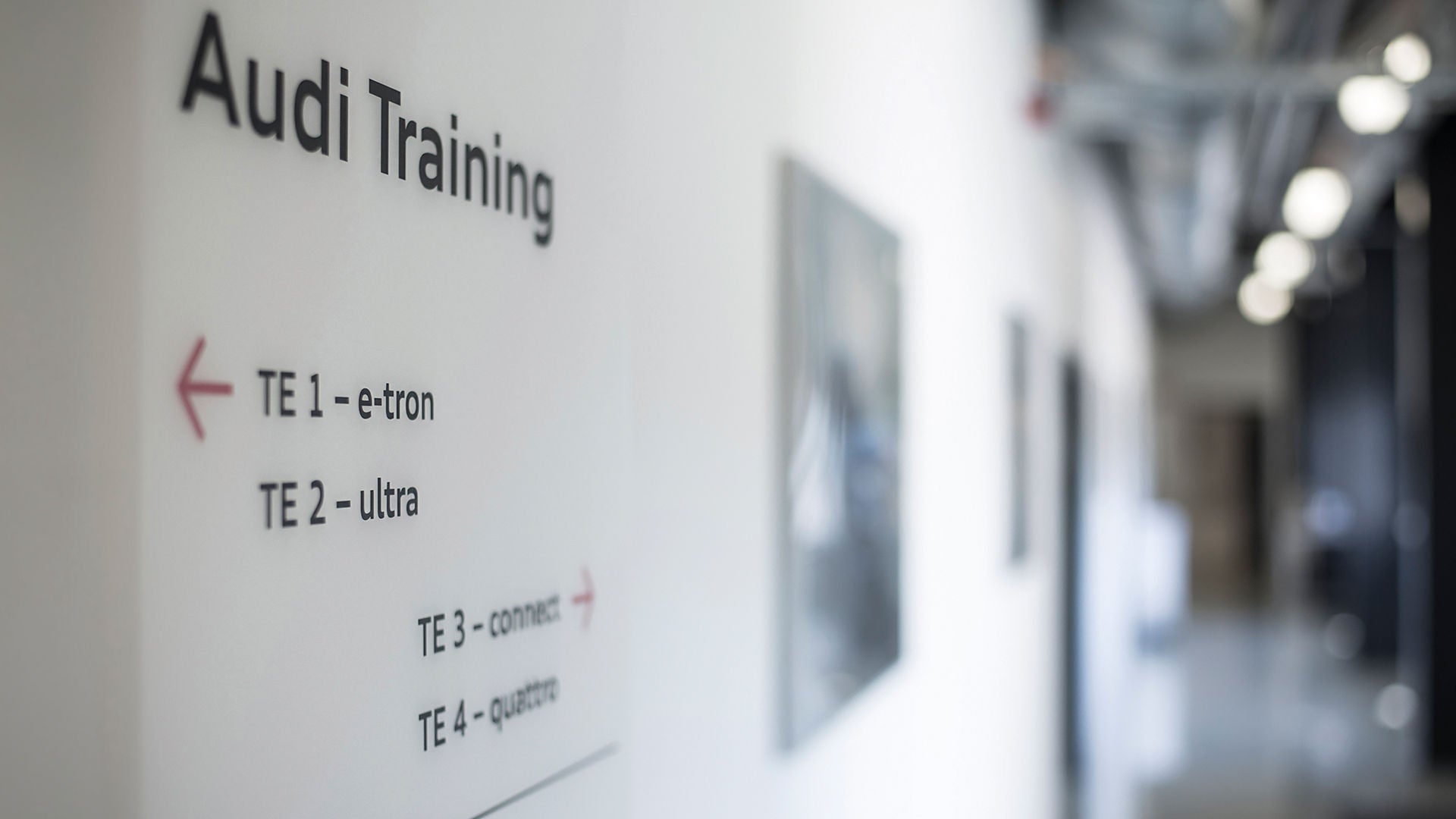 Wandbeschilderung mit dem Text "Audi Training" und Richtungsangaben zu Schulungsräumen wie „TE 1 – e-tron“ und „TE 3 – connect“.