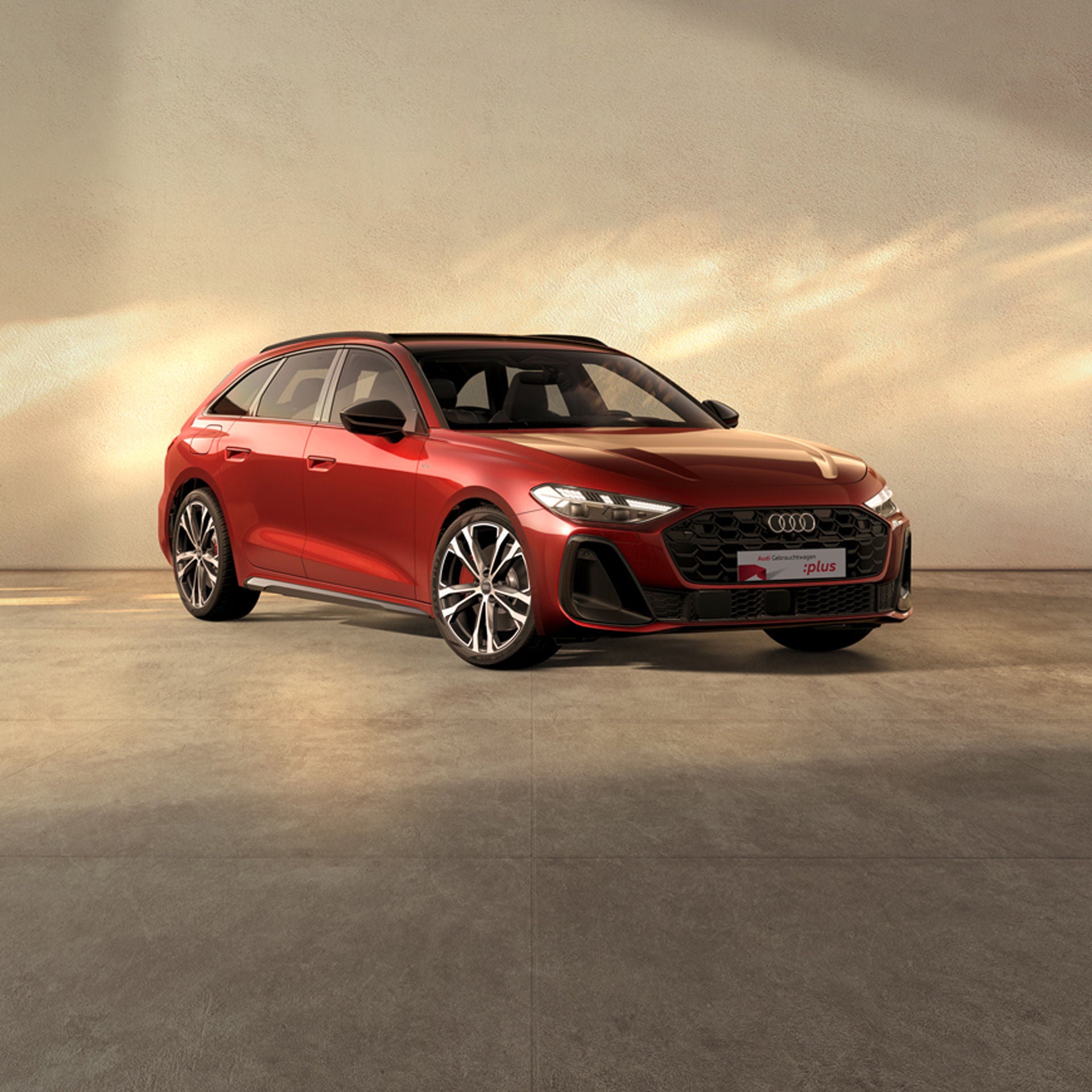 Ein roter Audi A5 steht auf einer beigen Fläche bei einfallendem Sonnenlich. Am Rand sind Kirschblüten zu sehen.
