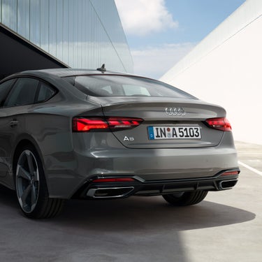 Audi A5 Sportback parked outdoors, showing the rear side of the grey vehicle.