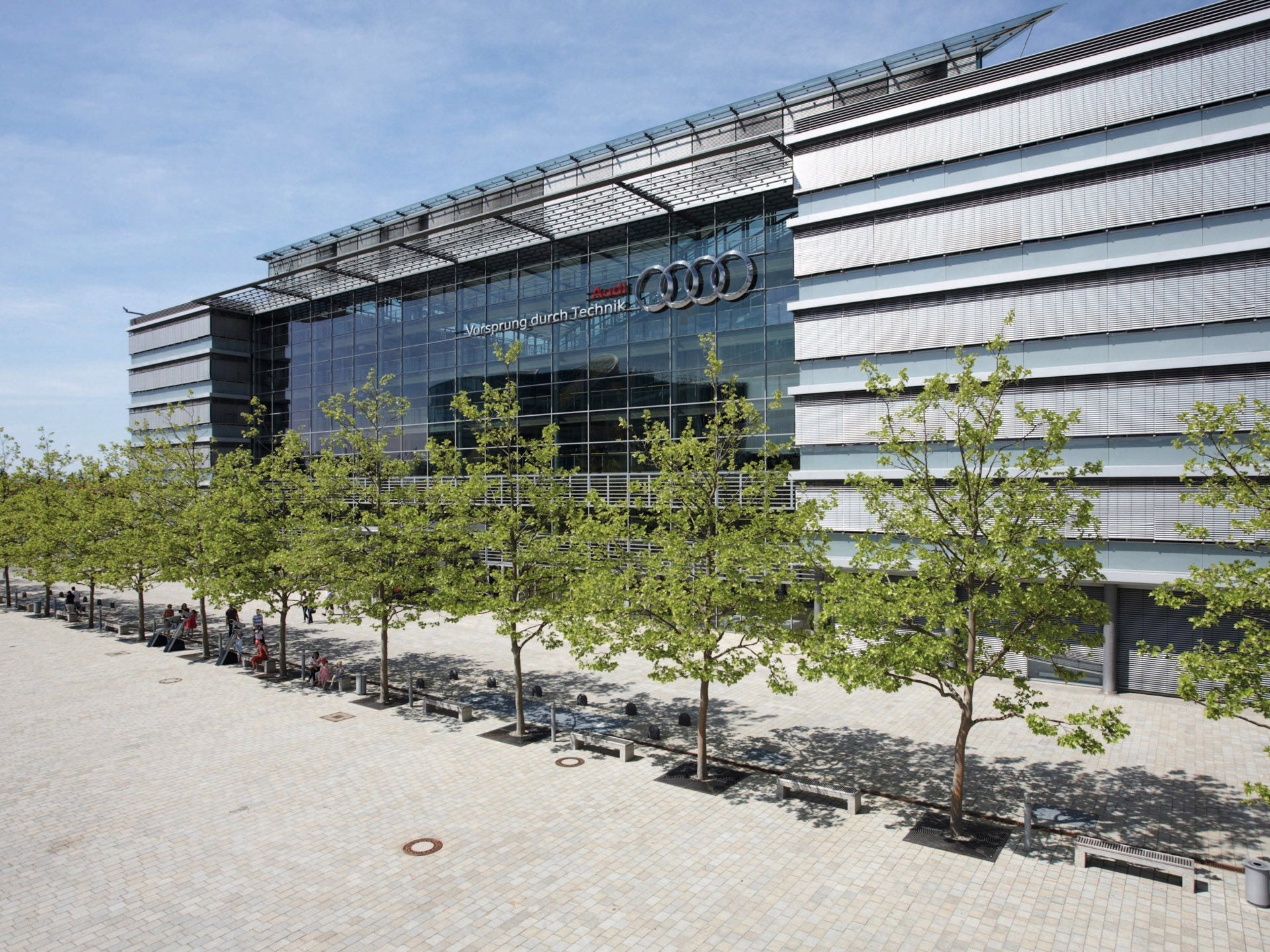 Image of a row of trees in front of the façade of the AUDI AG headquarters