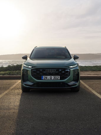 Side view of the Q5 SUV in anthracite in front of a modern building on the coast.
