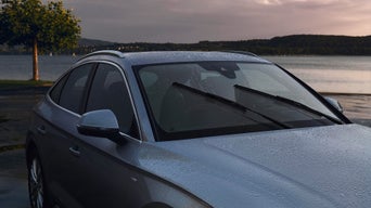 Ein grauer Audi steht im Regen mit Aerowischern, die in Funktion sind