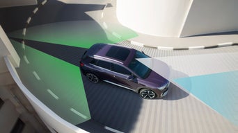 Audi Q4 arriving into a car park and turning corner with graphics illustrating sensors field of vision.