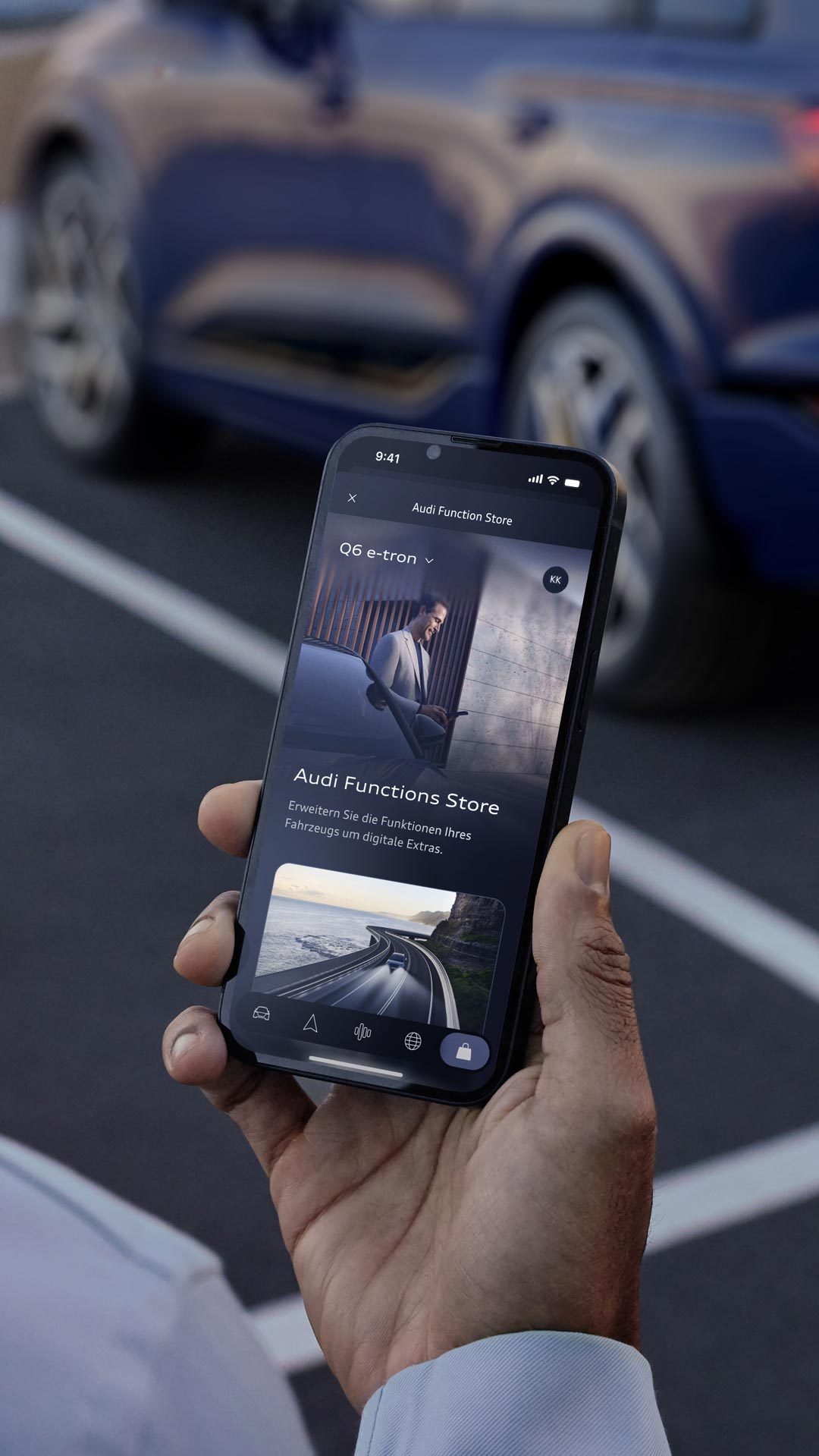 Mann in grauem Anzug steht neben einem Audi und blickt lächelnd auf ein Smartphone, im Hintergrund moderne Hausfassade.