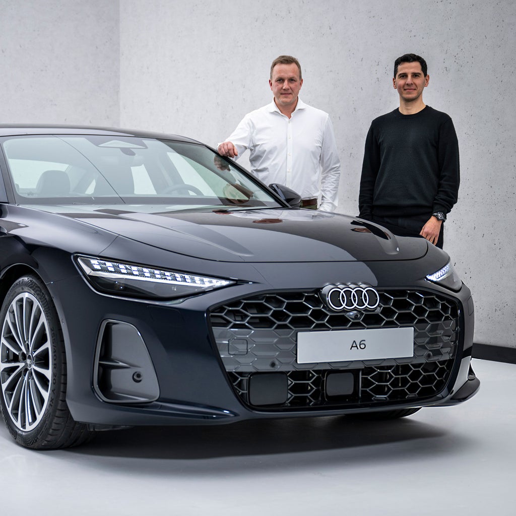 Sebastian Weiper und Francesco d’Amore stehen seitlich hinter der Motorhaube einer schwarzen Audi A6 Limousine.