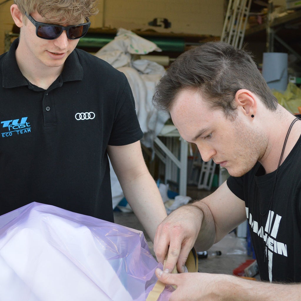 Two men tape something up with a plastic bag