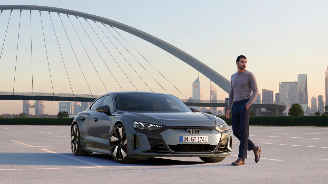 Audi car in front of a bridge and a man standing in front of it