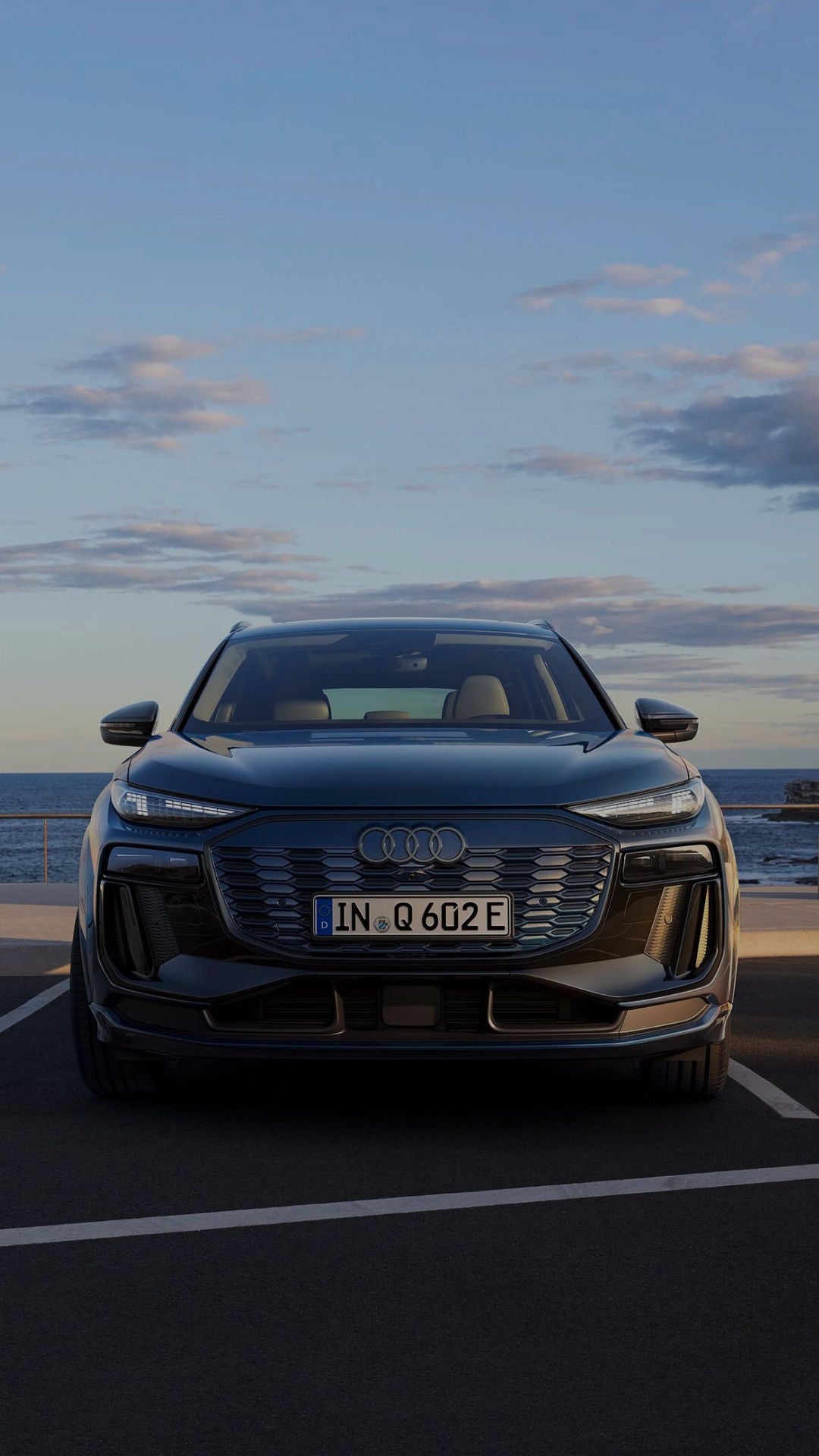 Parked Audi vehicle facing us with the Audi badge, headlights and windshield visible