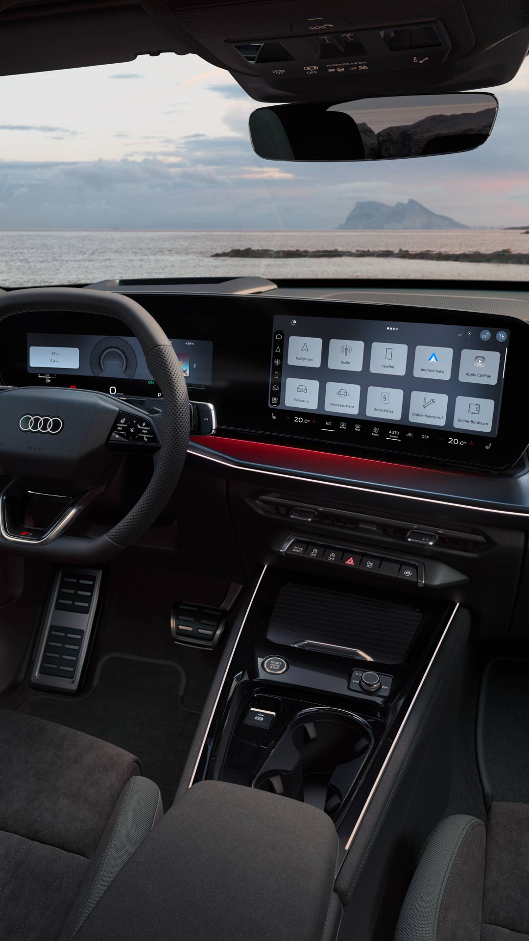 Blick von hinten auf das Cockpit des Q3 Sportback mit Lenkrad, Panoramadisplay und rotem Ambiente-Lichtpaket. Durch die Frontscheibe ist das Meer zu sehen.