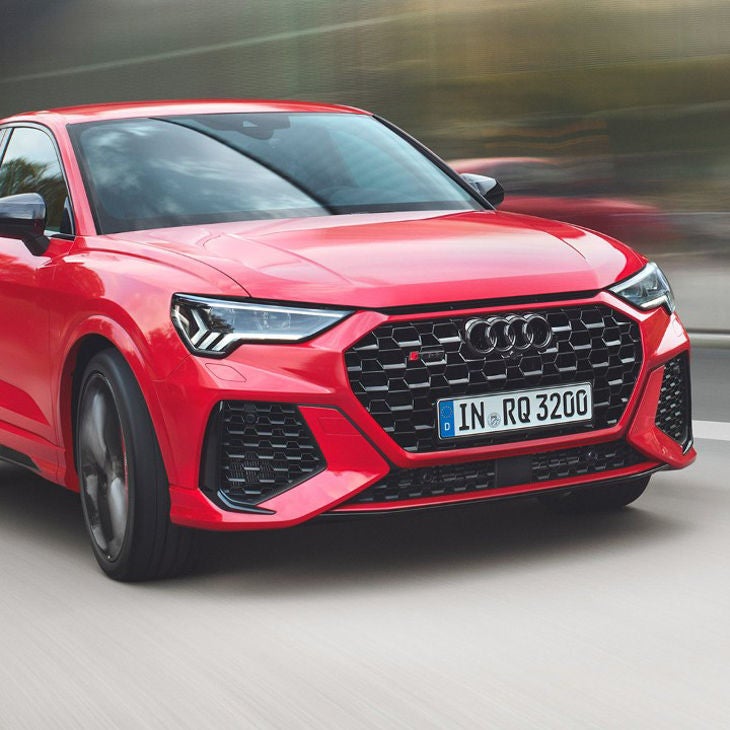 A red Audi car in motion on a blurred background.