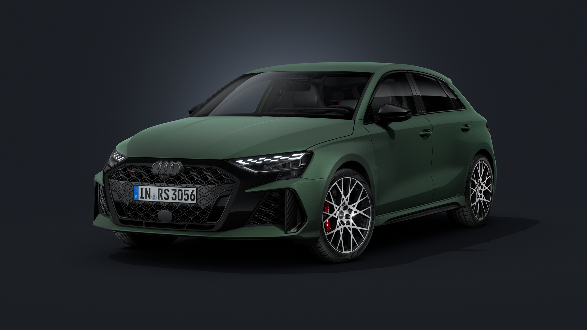 Audi RS 3 Sportback i District Green med polarmatt finish, sedd snett framifrån mot en mörk bakgrund.