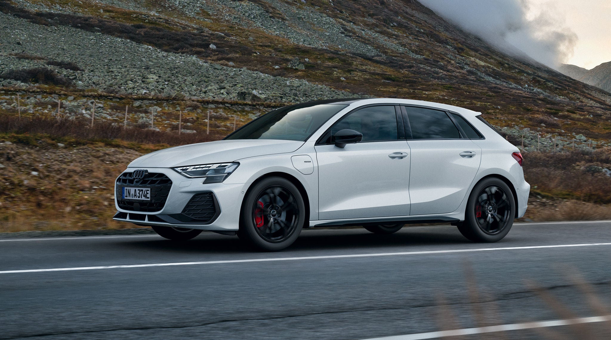 vista laterale parziale di Audi A3 Sportback e-hybrid in marcia su strada di montagna