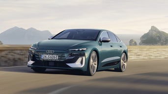 The S6 Sportback e-tron with its sloping rear profile as it drives along a winding coastal road.