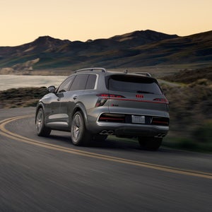 The Audi SQ9 is seen from an oblique rear view as it negotiates a bend on a country road, with the sea to its left and mountain ranges in the background.
