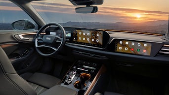 Blick ins Audi-Cockpit mit großem Display und Navigationskarte bei Sonnenuntergang.