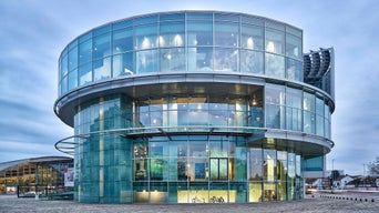 Round, modern glass building with several floors in daylight.