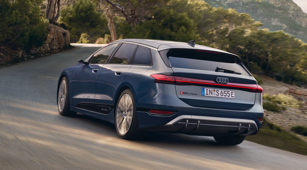 Der S6 Avant e-tron aus schräger Heckansicht fährt durch kurvige Straßen mitten in der Natur. Im Hintergrund sind Bäume und Berge zu sehen.