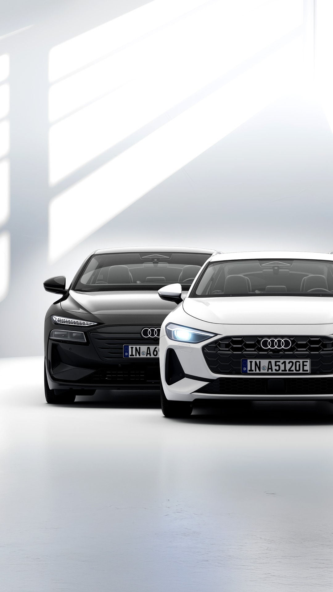 Frontalansicht eines weißen Audi A5 und eines schwarzen Audi A6 in heller lichtdurchfluteter Atmosphäre