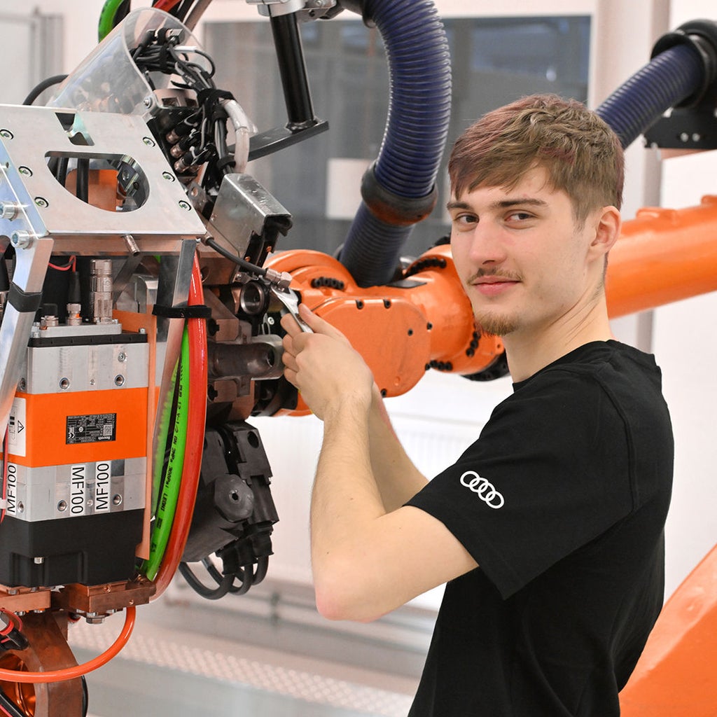 Noah schaut in die Kamera und schraubt an einer Machine herum