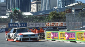 A racing car on a racetrack in front of skyscrapers