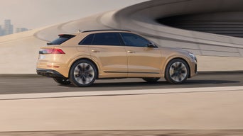 The Audi Q8 is performing very impressively. with a city visible in the background. 