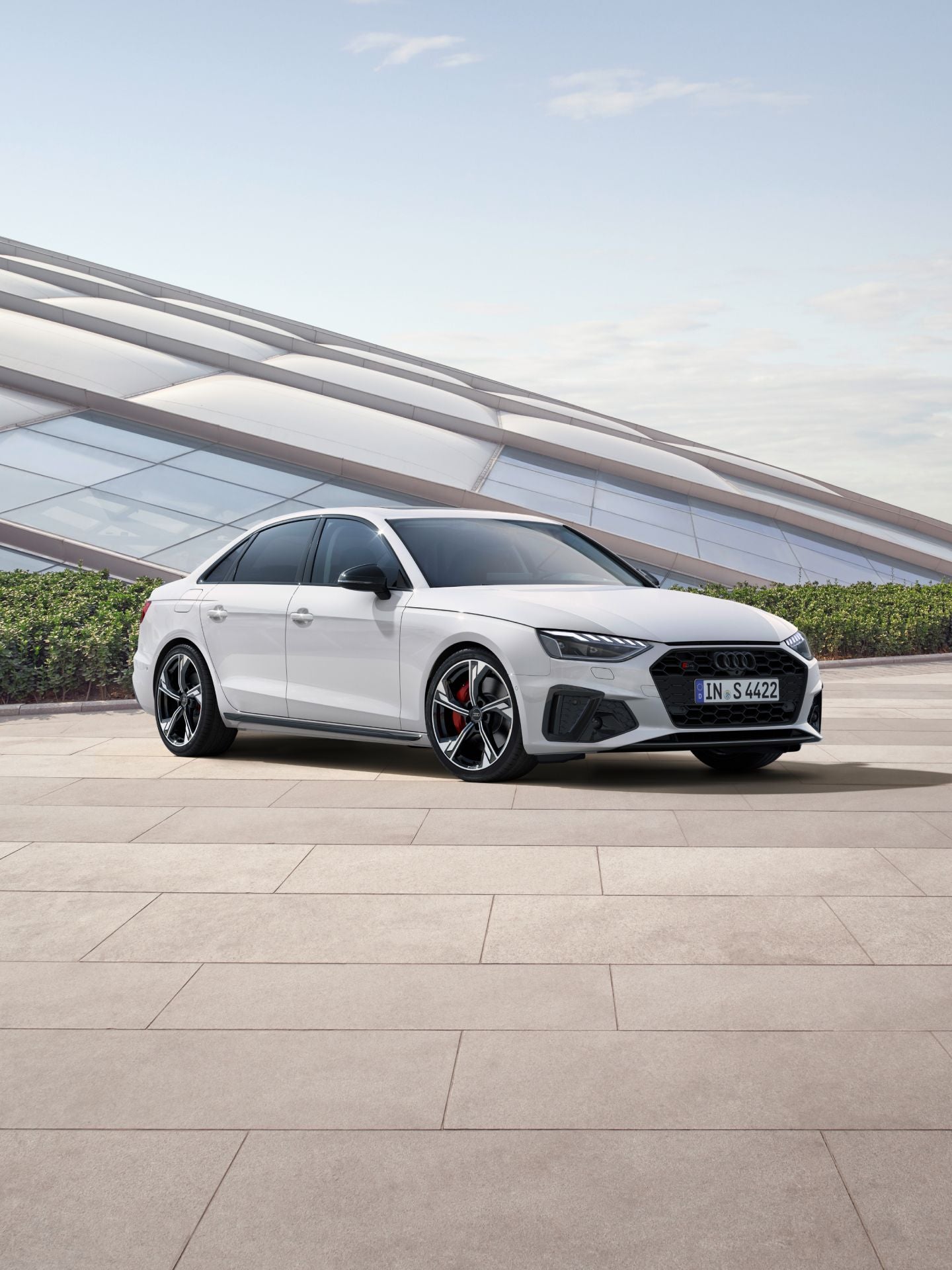 A white Audi sedan parked outdoors with modern architecture in the background.