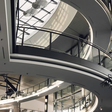 Moderne Glasfassade eines Audi-Gebäudes mit sichtbaren Autos und Ausstellungsflächen im Inneren.