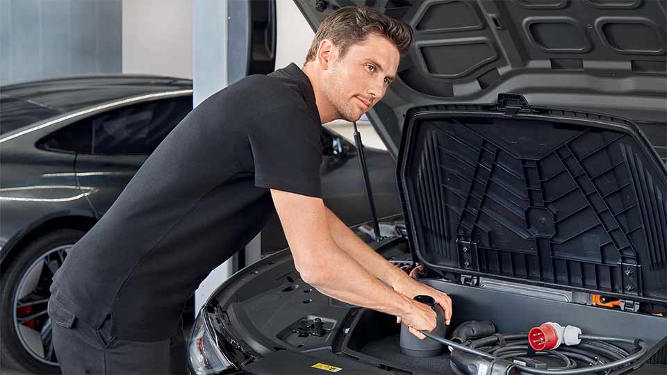 開いたボンネット内に両手を入れ作業する人物