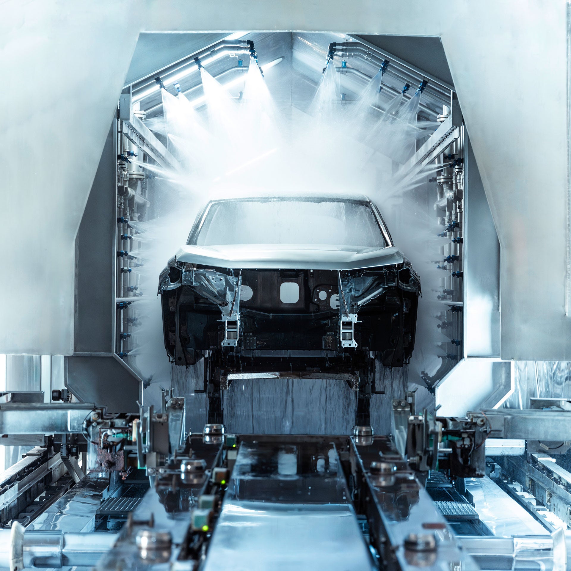 Ein Auto wird in der Lackiererei von Applikationsrobotern besprüht