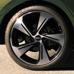 Close-up of Audi A3 Sportback's alloy wheel, centre featuring Audi logo, on tarmac.