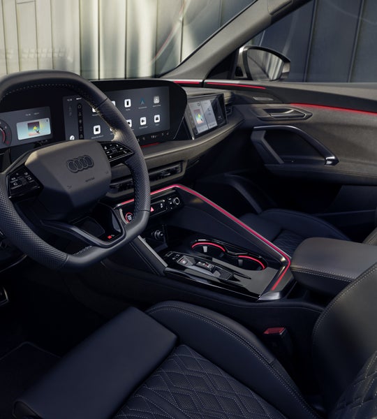 Blick in das Cockpit des SQ5 Sportback durch das Fahrerfenster. Zu sehen sind die verschiedenen Displays im Cockpit, sowie die rote Ambiente Beleuchtung.