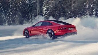 Roter Audi RS e-tron GT performance driftet auf Schneepiste vor verschneiten Bäumen.