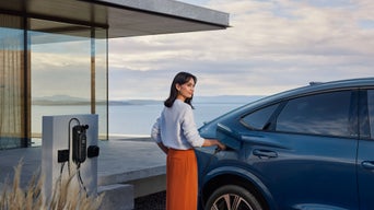 A woman plugging in the EV charger cable on a blue Audi SQ6 Sportback e-tron