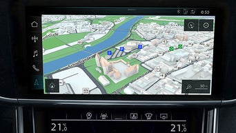 Navigationsanzeige auf dem Audi-Display mit 3D-Kartenansicht eines Stadtgebiets entlang eines Flussufers.