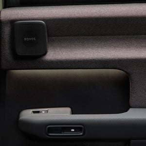 Close-up of the Audi A2 e-tron’s interior door, featuring a Sonos speaker and a storage compartment.