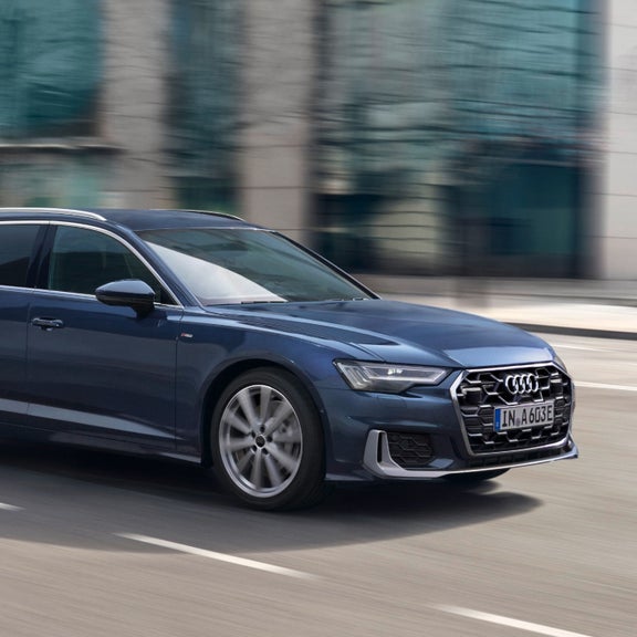 A blue Audi car in motion on a blurred city street.