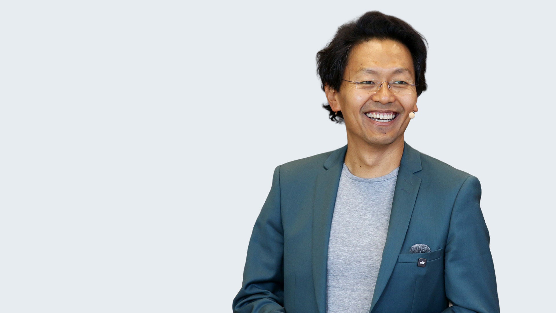 Chan-jo Jun: Porträt eines lächelnden asiatischen Mannes mit Brille im Blazer vor hellgrauem Hintergrund.