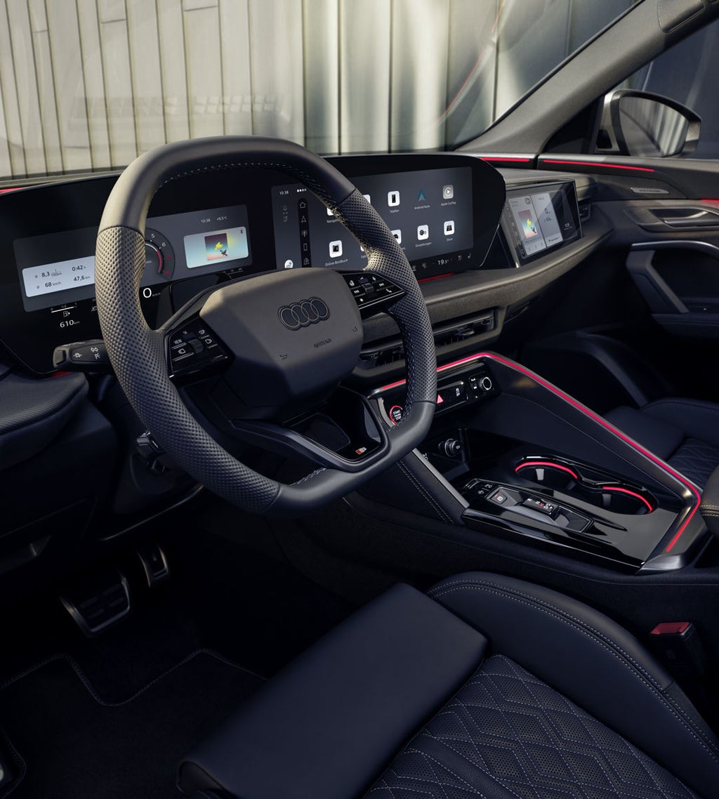 Blick in das Cockpit des SQ5 Sportback durch das Fahrerfenster. Zu sehen sind die verschiedenen Displays im Cockpit, sowie die rote Ambiente Beleuchtung.
