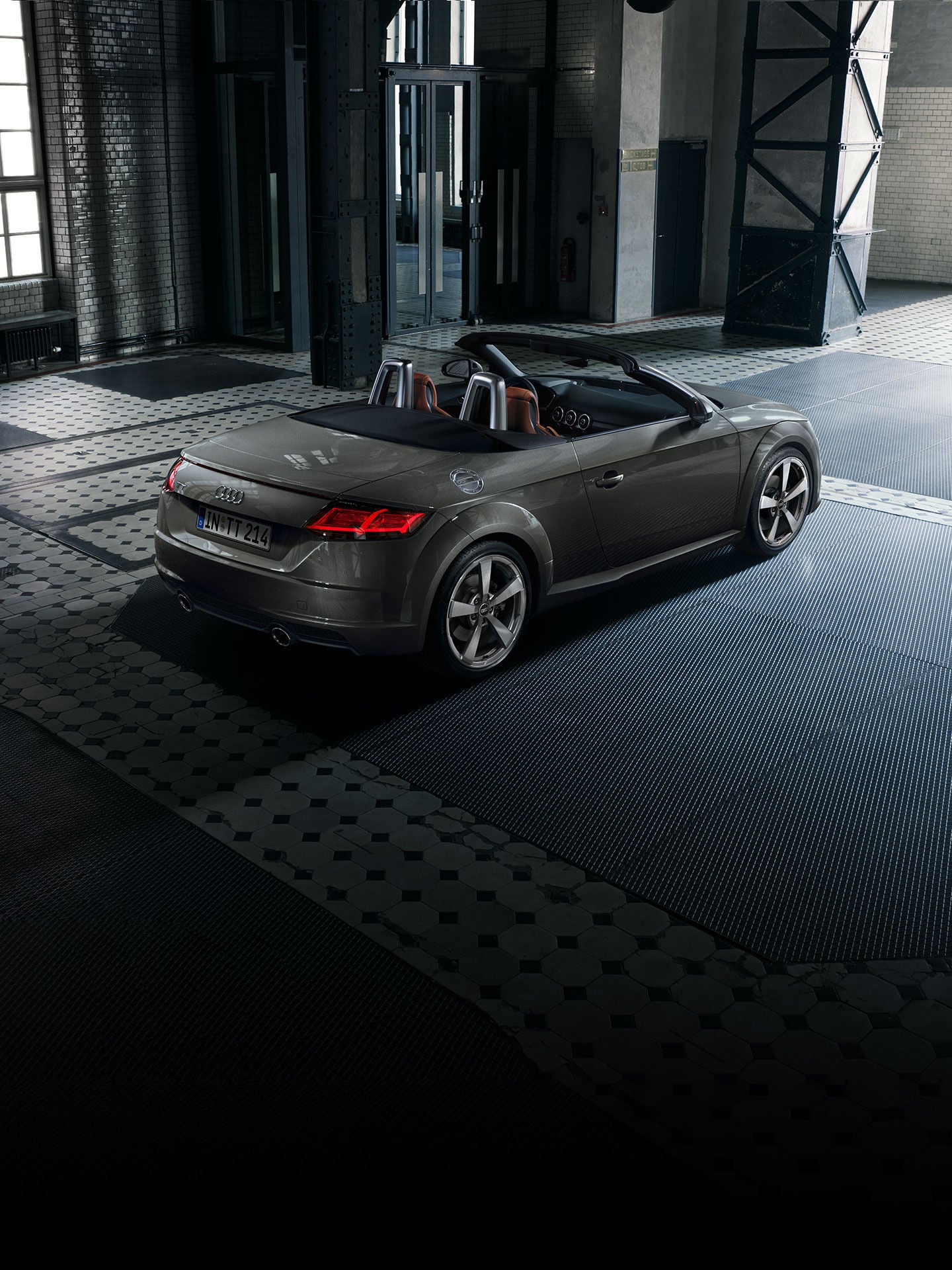 Dark grey soft-top Audi TT Roadster parked in a modern garage.