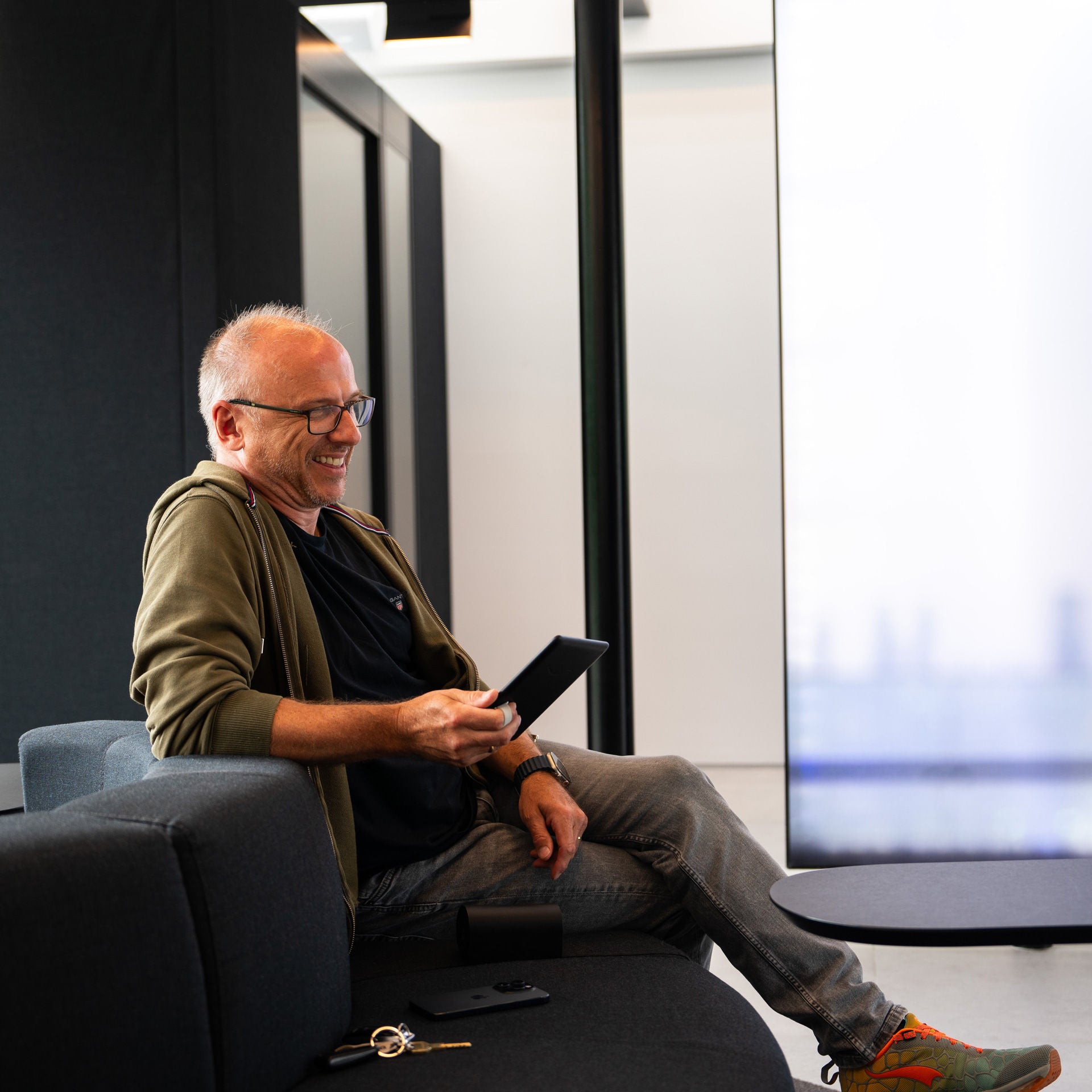Thilo sitzt auf einem Sofa mit einem E-Reader in der Hand
