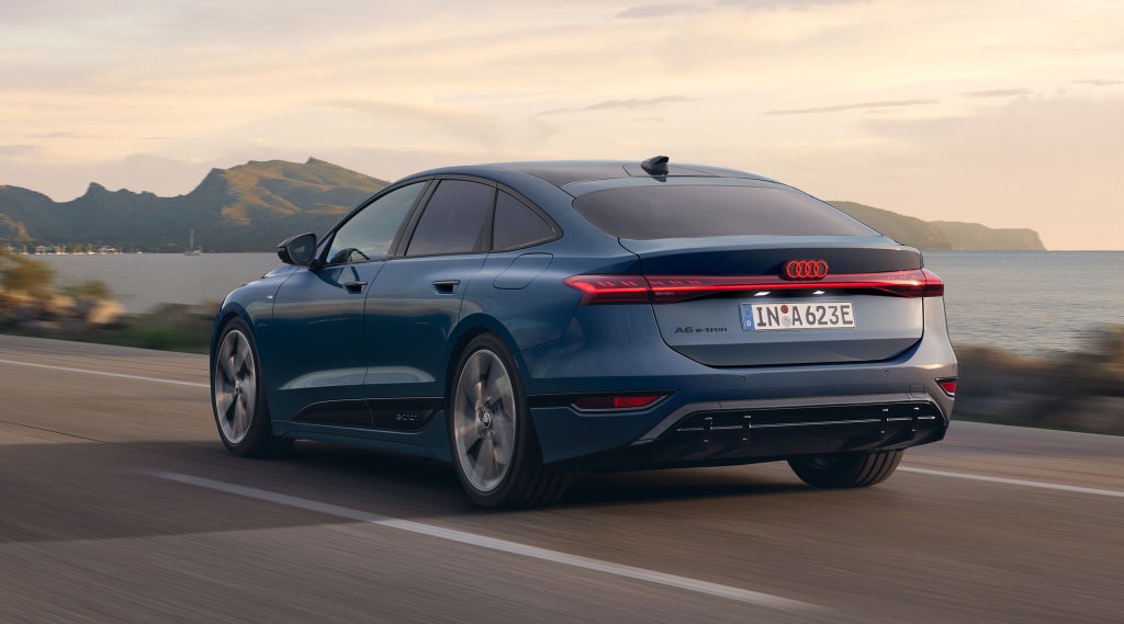 Vrouw staat achter de voorkant van een Audi A6 Sportback e-tron.