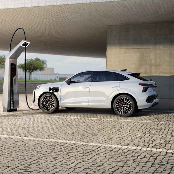 Audi Q3 Sportback e-hybrid Ricaricare presso una colonnina di ricarica pubblica in una posizione di parcheggio di ultima generazione.