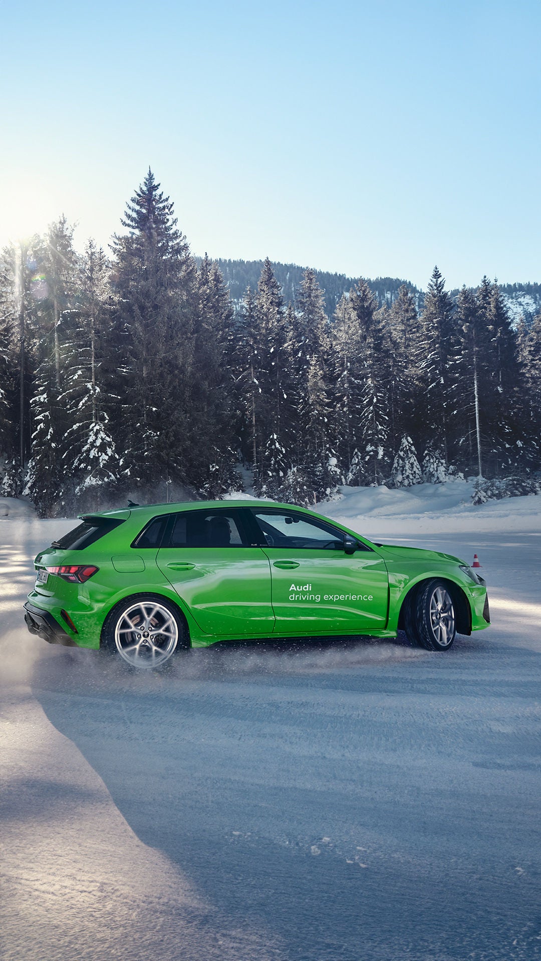 Light green Audi RS 3 Sportback with Audi driving experience logo drifting in the snow.