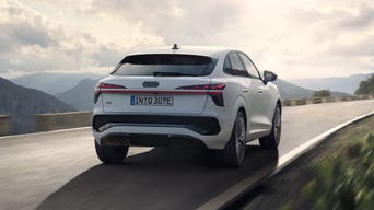 Ein weißer Q3 Sportback e-hybrid fährt auf einer Landstraße in einer bergigen Landschaft.